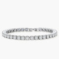 Sterling silver tennis bracelet with continuous row of brilliant moissanite stones and secure clasp closure on cream background.