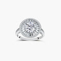 Brilliant round moissanite center stone with baguette and round halo accents in sterling silver setting on light background.