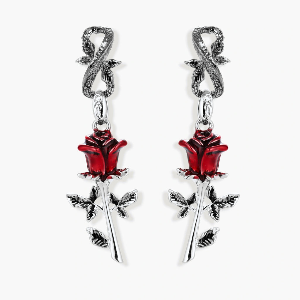 Gothic dangle earrings featuring silver serpent hooks with red enamel roses and metallic stems on white background.