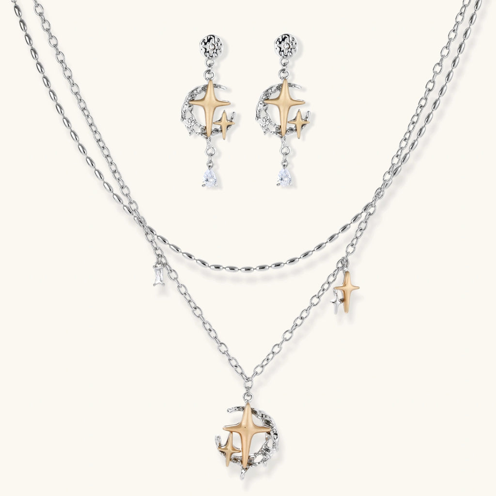 Delicate eco-brass jewelry set featuring gold star and silver moon crescents with clear zirconia crystal drops on cream background