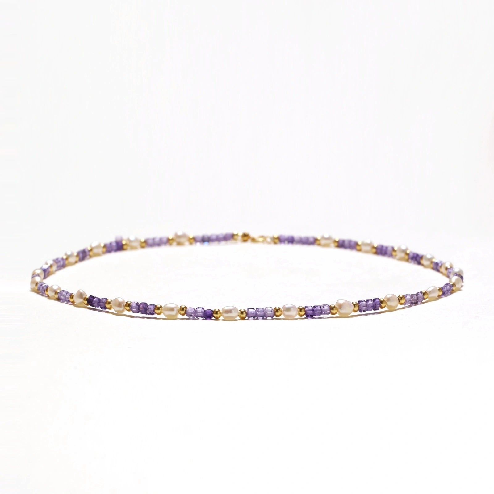 Delicate 18K gold vermeil necklace with alternating lavender zirconia beads and white freshwater pearls on cream background