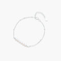 Delicate rhodium-plated silver chain bracelet with row of small baroque pearls centered on white background.