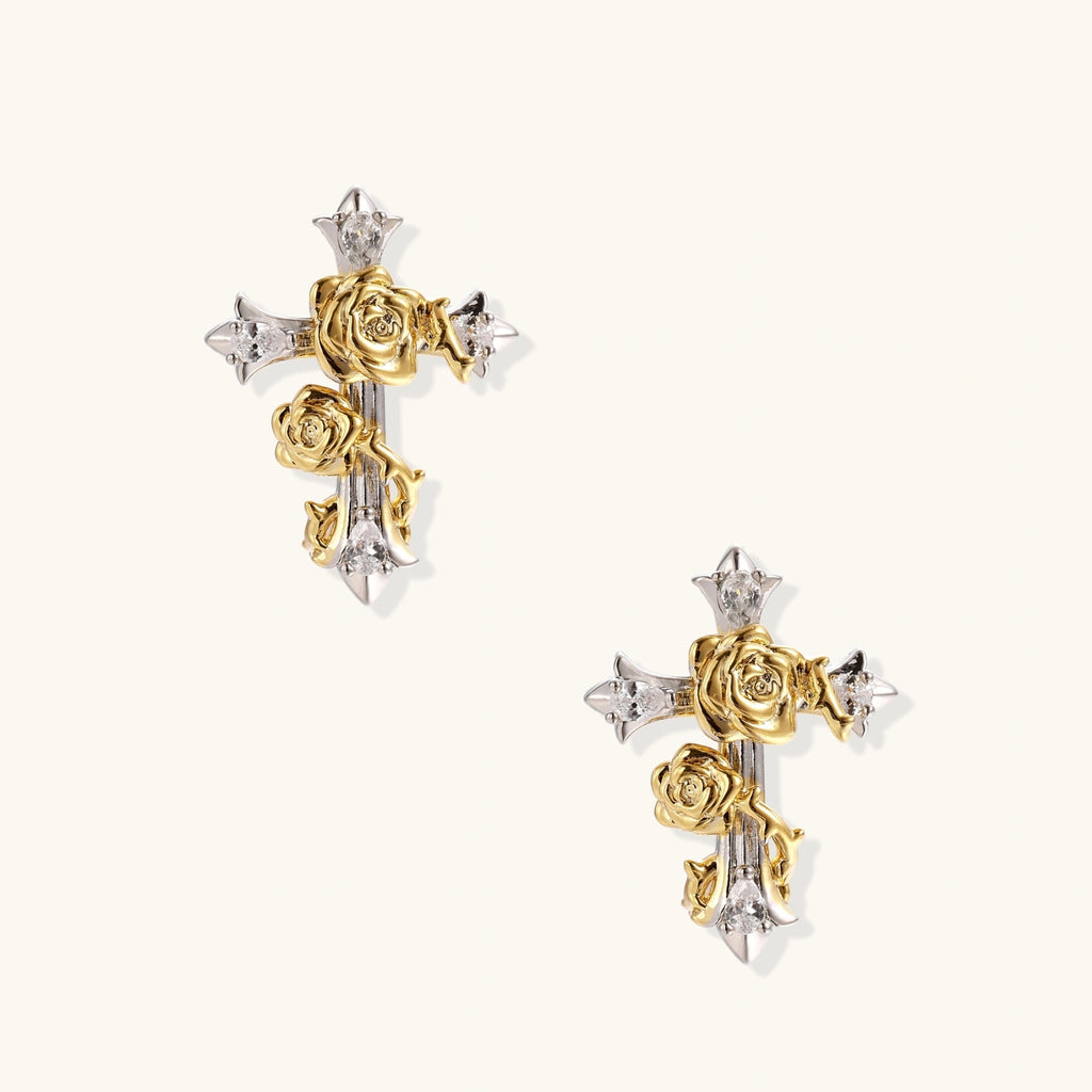 Gold-plated cross earrings with dimensional roses and crystal details on cream background, 18k gold over brass construction.