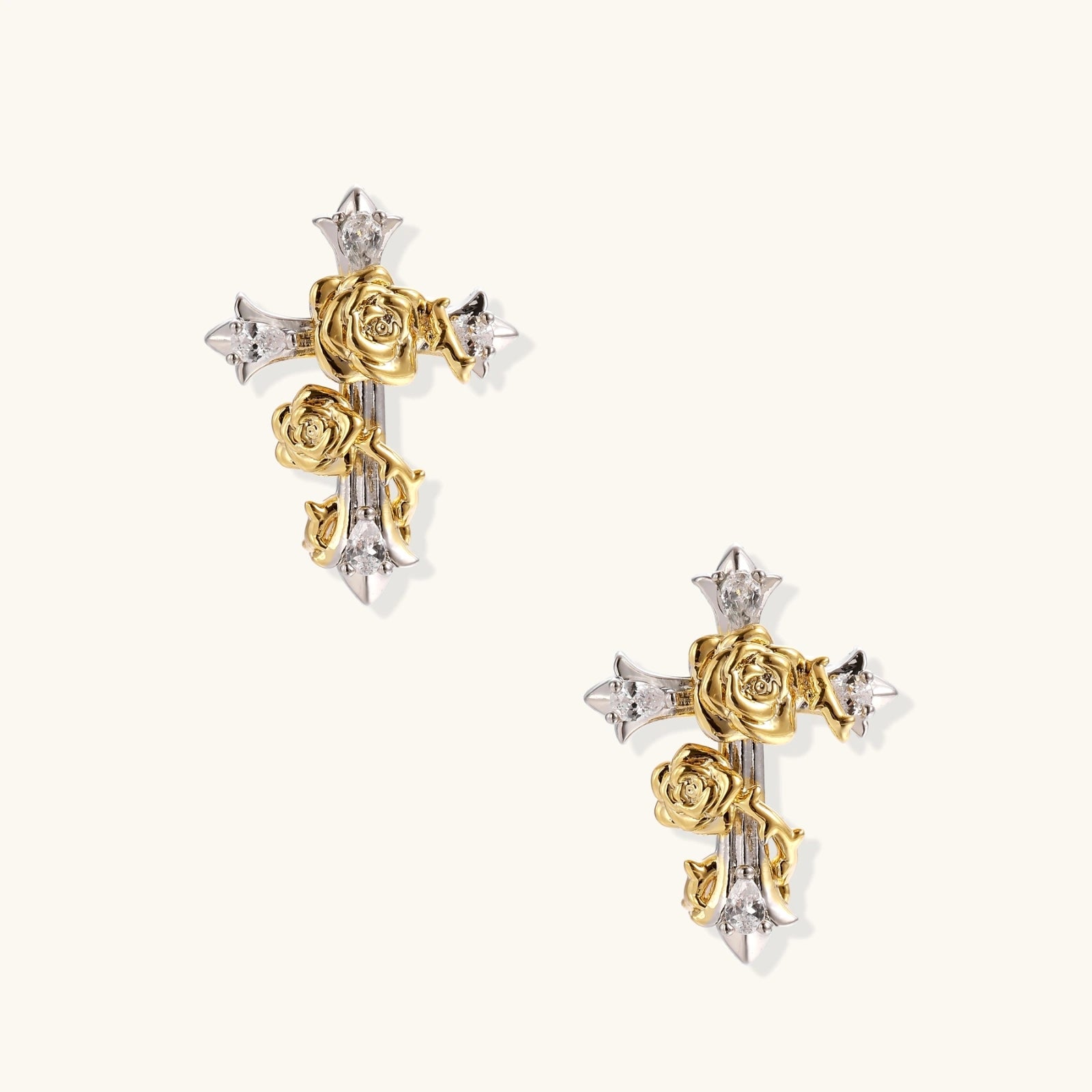 Gold-plated cross earrings with dimensional roses and crystal details on cream background, 18k gold over brass construction.