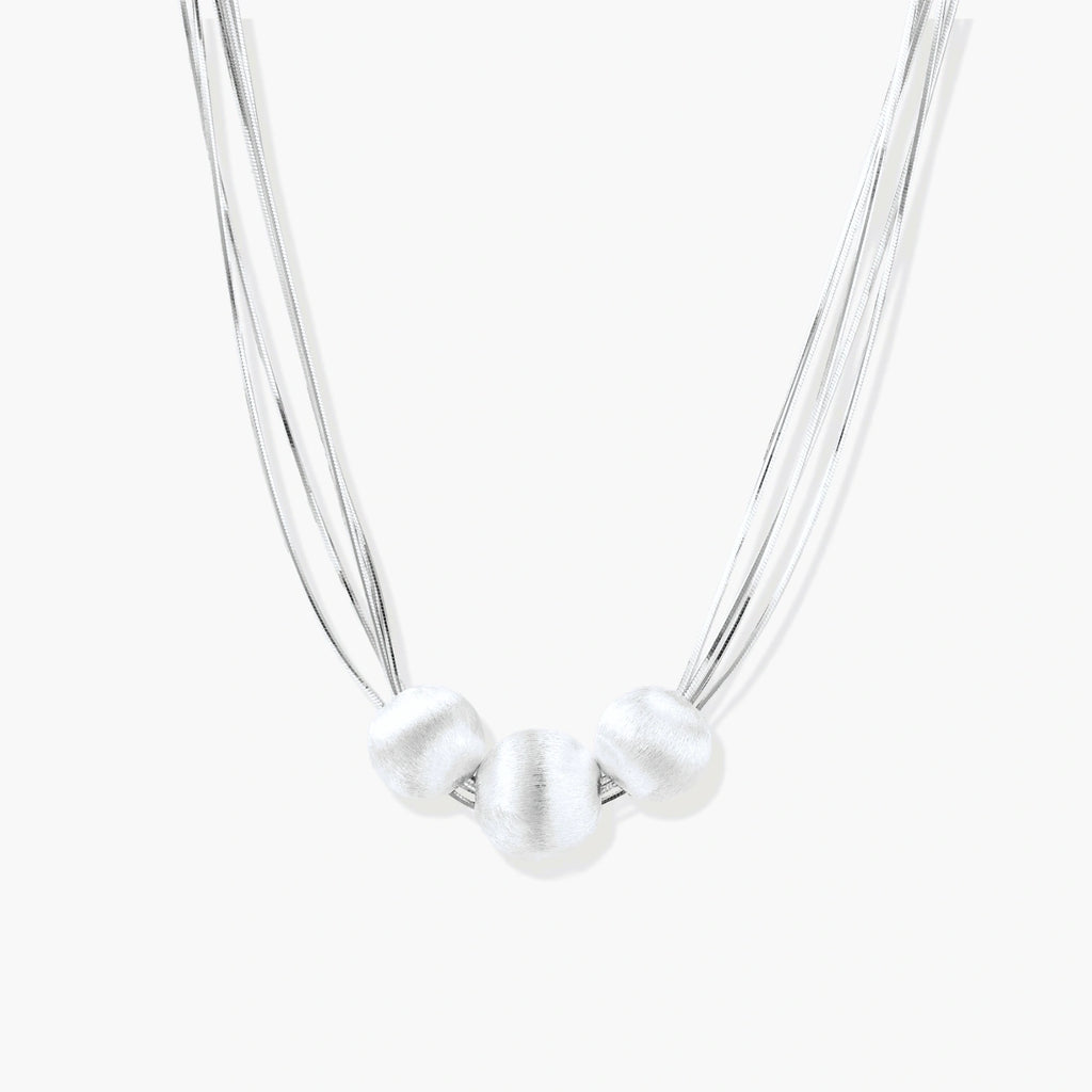 Sterling silver multi-strand necklace with three brushed round beads on cream background