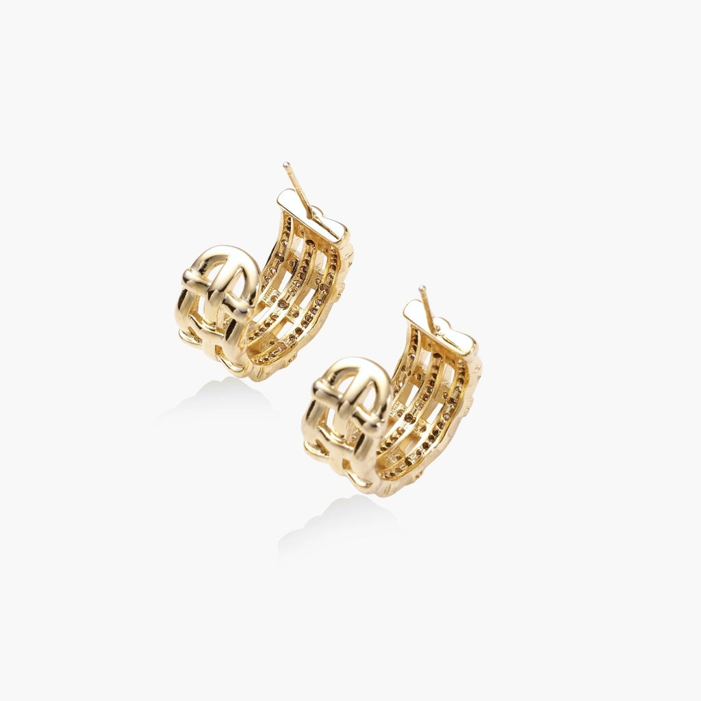 Gold-plated geometric hoop earrings with basket-weave lattice design and pavé crystal accents on cream background
