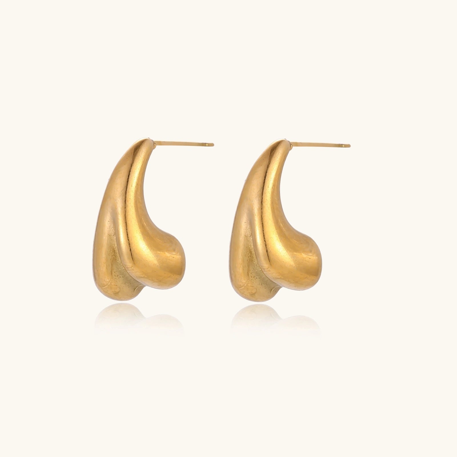 Organic sculptural gold stud earrings with fluid matte finish on cream background