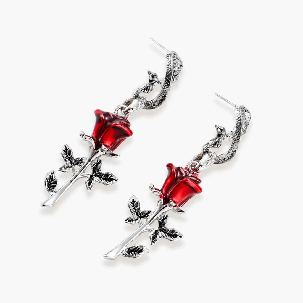 Gothic jewelry set with silver snake designs holding red enamel roses, featuring detailed leaf stems on cream background