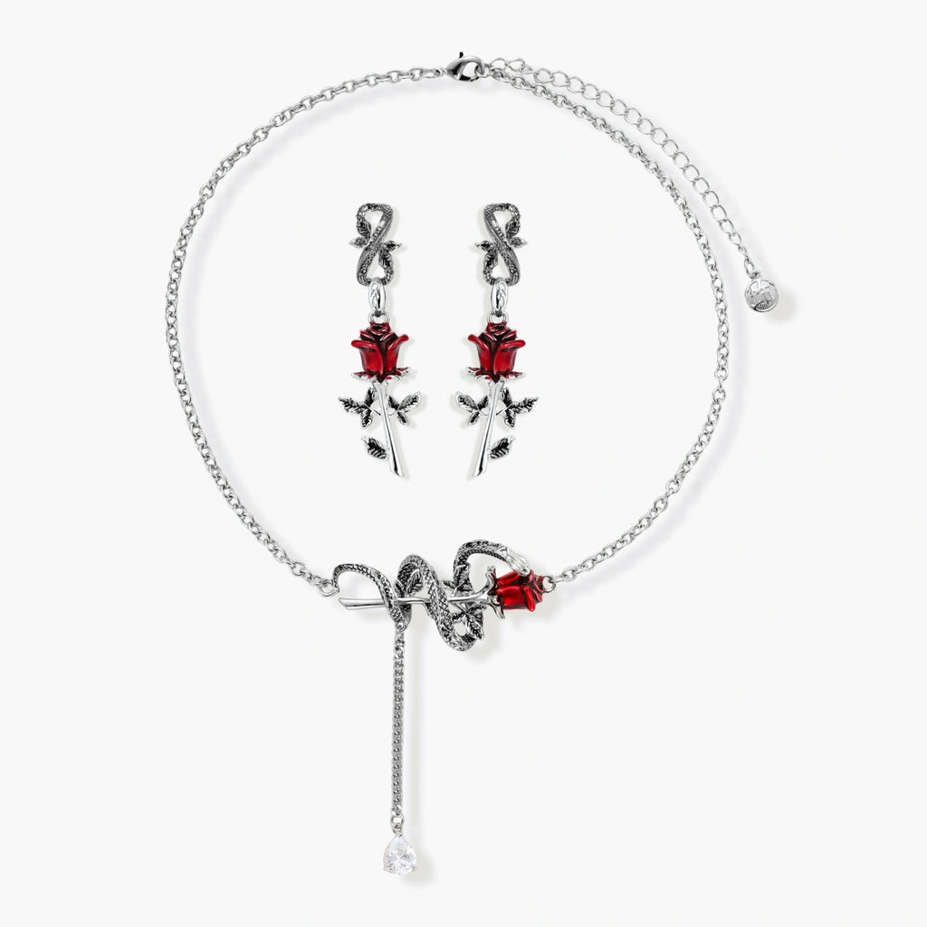 Gothic jewelry set with silver snake designs holding red enamel roses, featuring detailed leaf stems on cream background