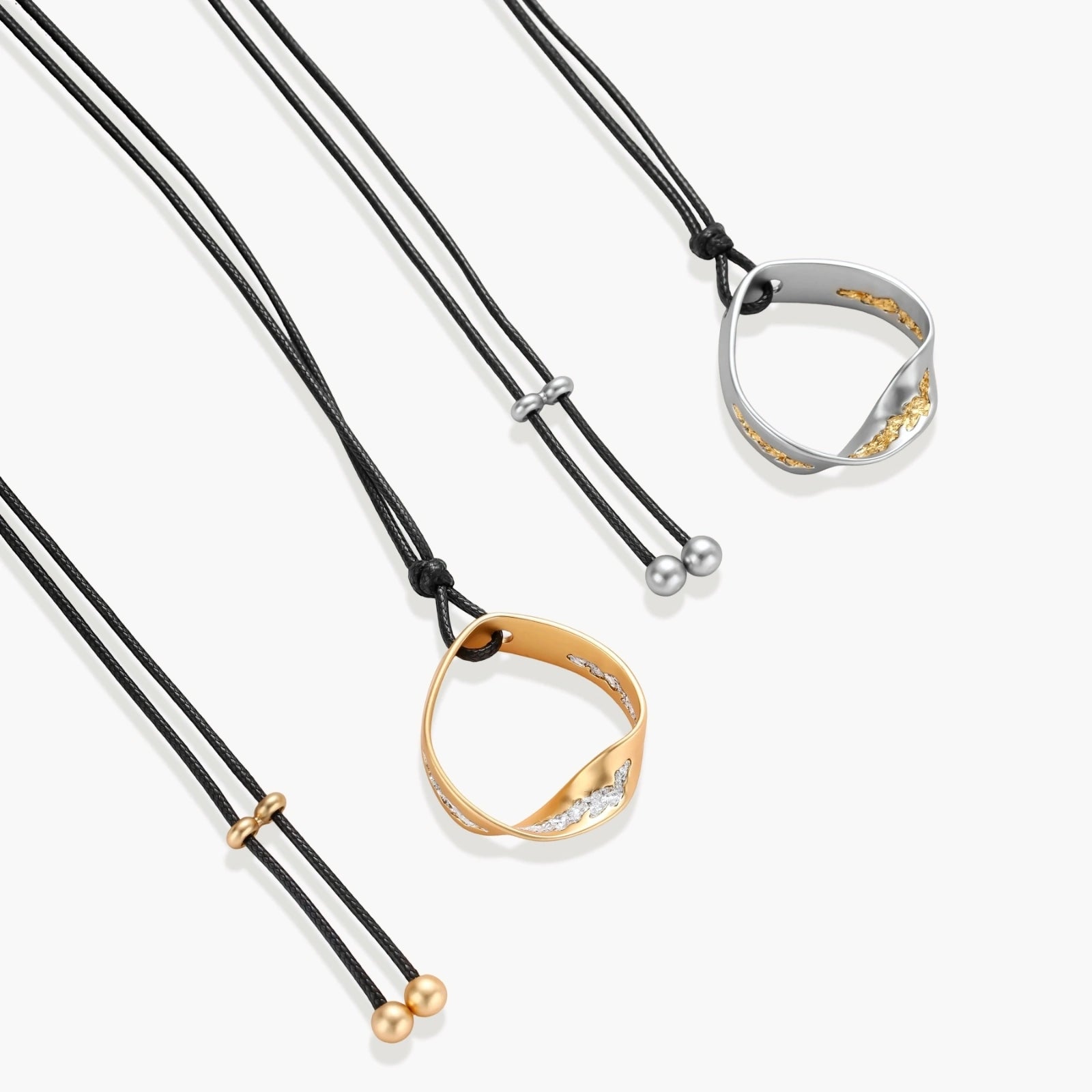 Adjustable black cord necklace with circular gold pendant featuring sparkly crystal accents on white background.