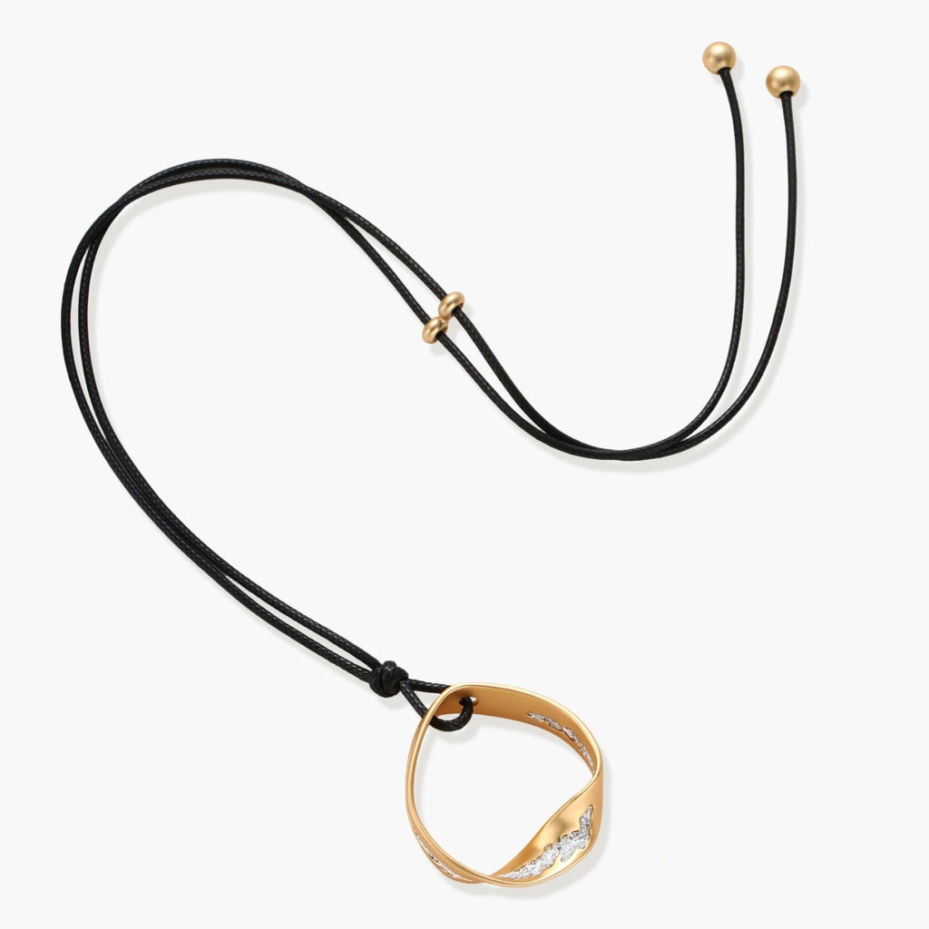Geometric circle pendant necklace with crystal cluster on adjustable black cord, available in gold and silver finishes.