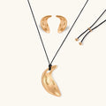 Gold-toned crescent moon pendant with textured surface on black adjustable cord, displayed with matching crescent earrings