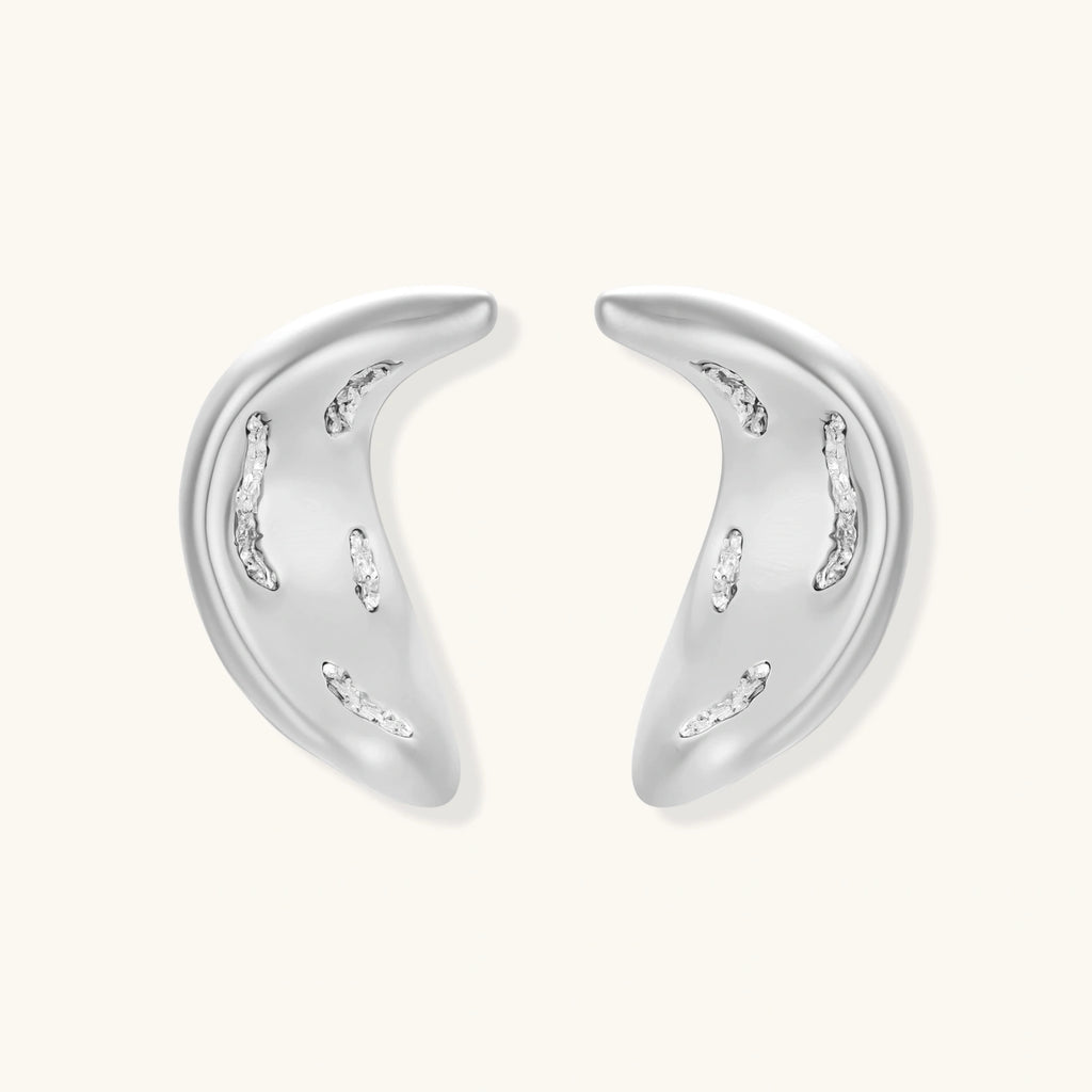 Crescent moon shaped pendant and earrings in eco-zinc alloy with curved crystal inlay patterns on light background.