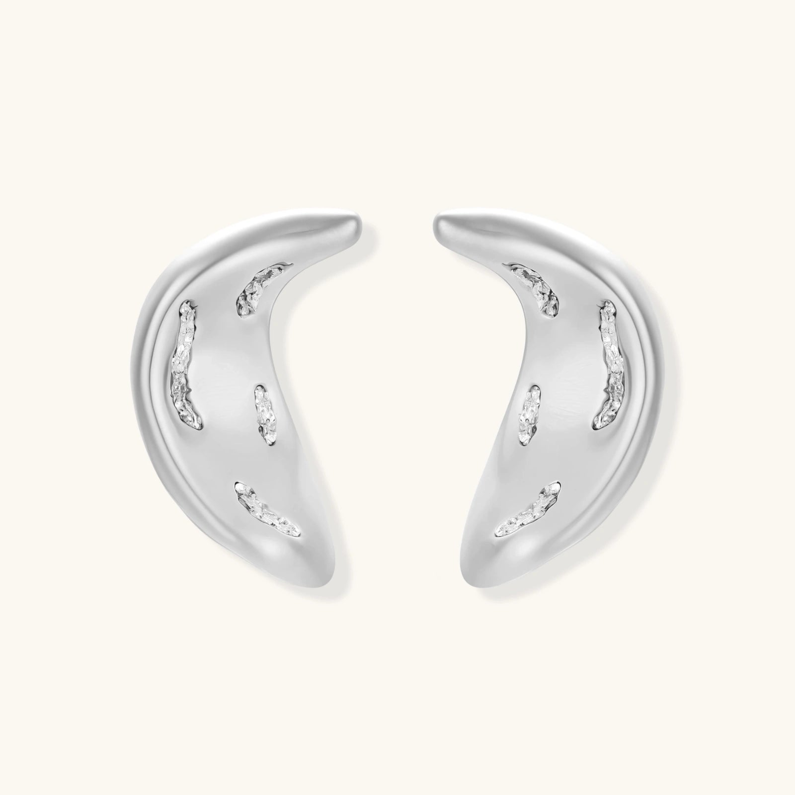Crescent moon shaped pendant and earrings in eco-zinc alloy with curved crystal inlay patterns on light background.
