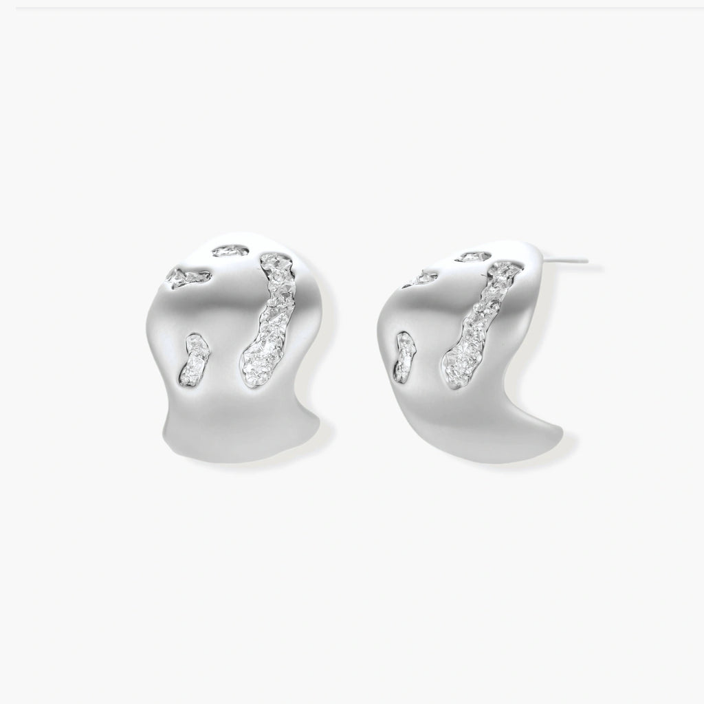 Organic shaped silver stud earrings with sparkling crystal details in flowing molten design on white background.