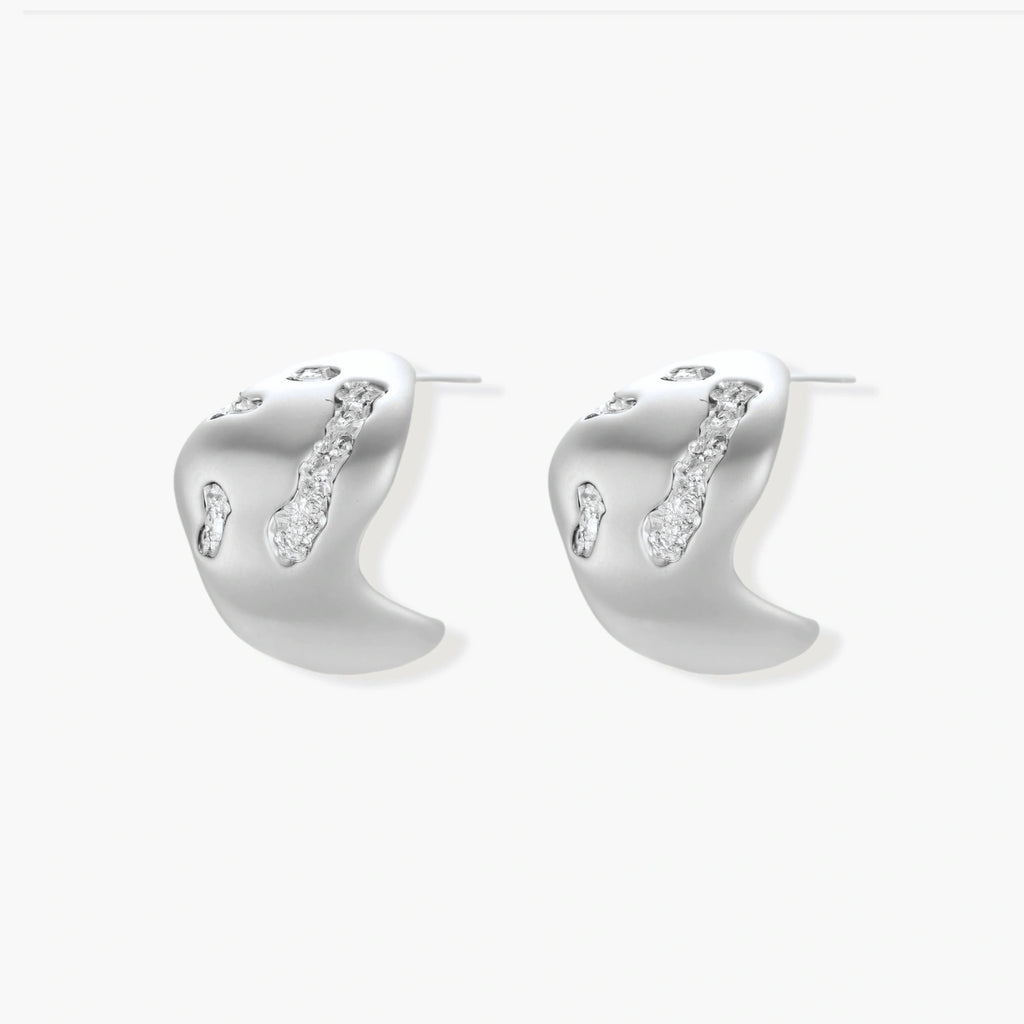 Organic shaped silver stud earrings with sparkling crystal details in flowing molten design on white background.