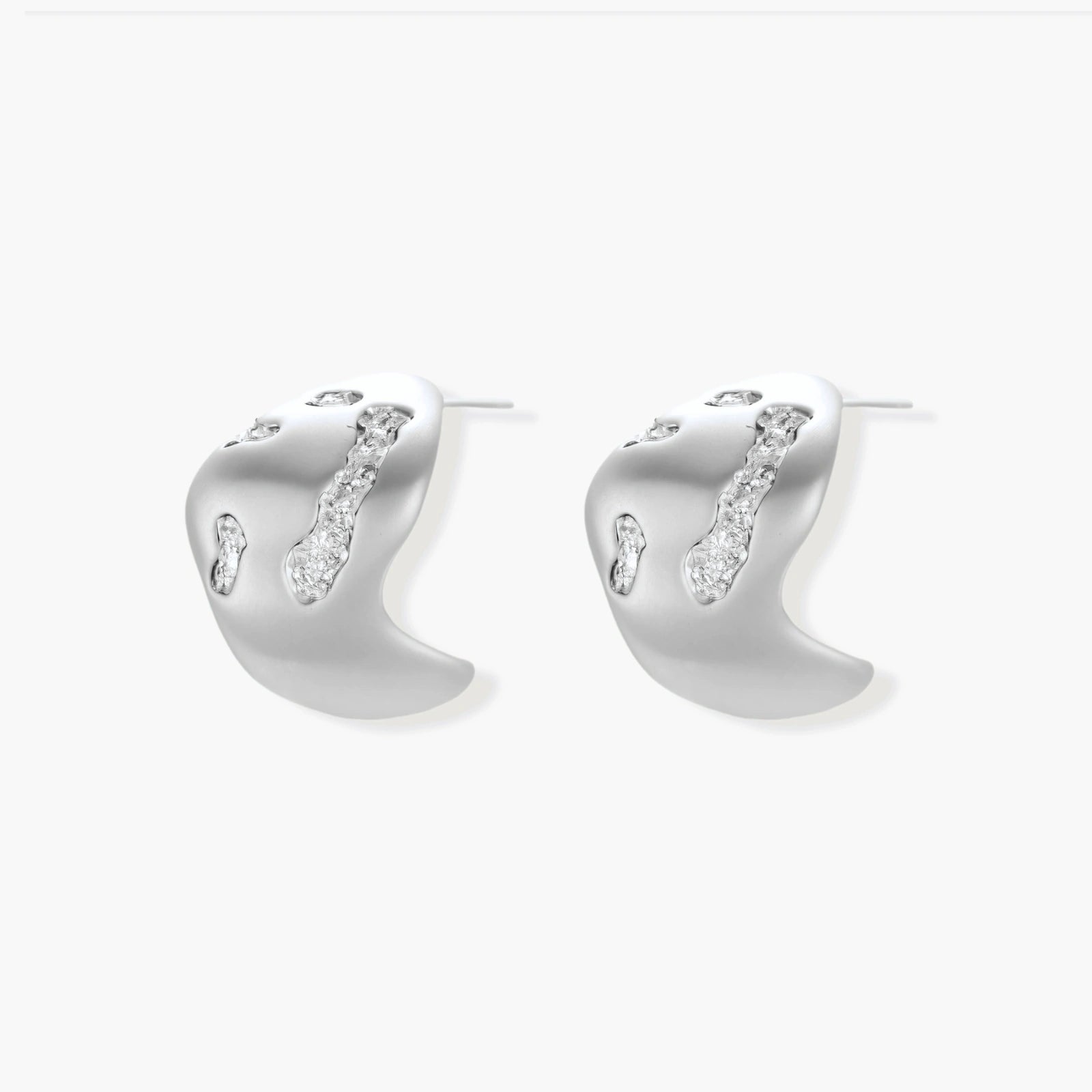 Organic shaped silver stud earrings with sparkling crystal details in flowing molten design on white background.