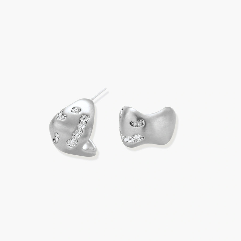 Organic shaped silver stud earrings with sparkling crystal details in flowing molten design on white background.
