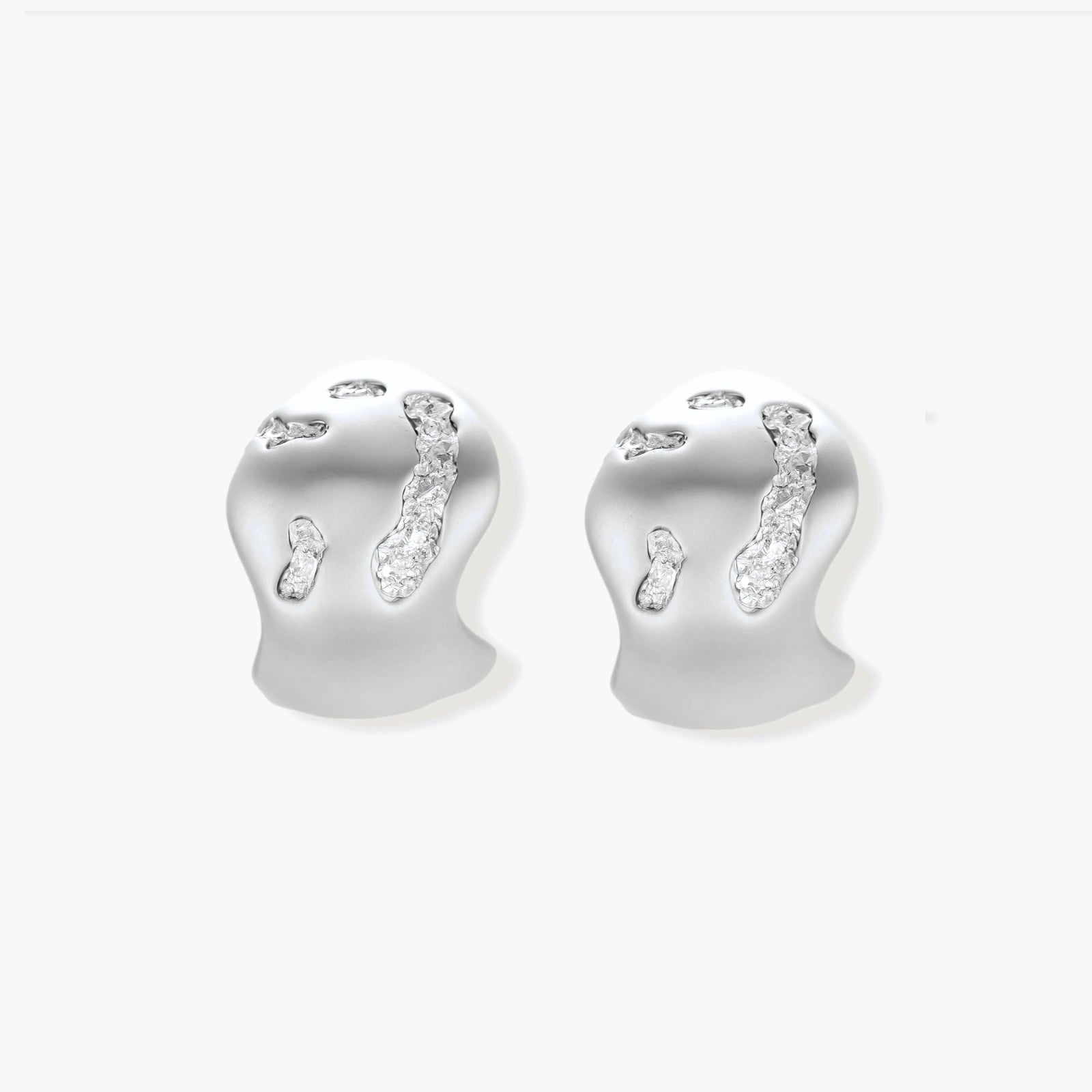 Organic shaped silver stud earrings with sparkling crystal details in flowing molten design on white background.