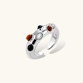 Adjustable platinum-plated ring with multiple oval cabochon stones in black, amber, and white tones on neutral background.