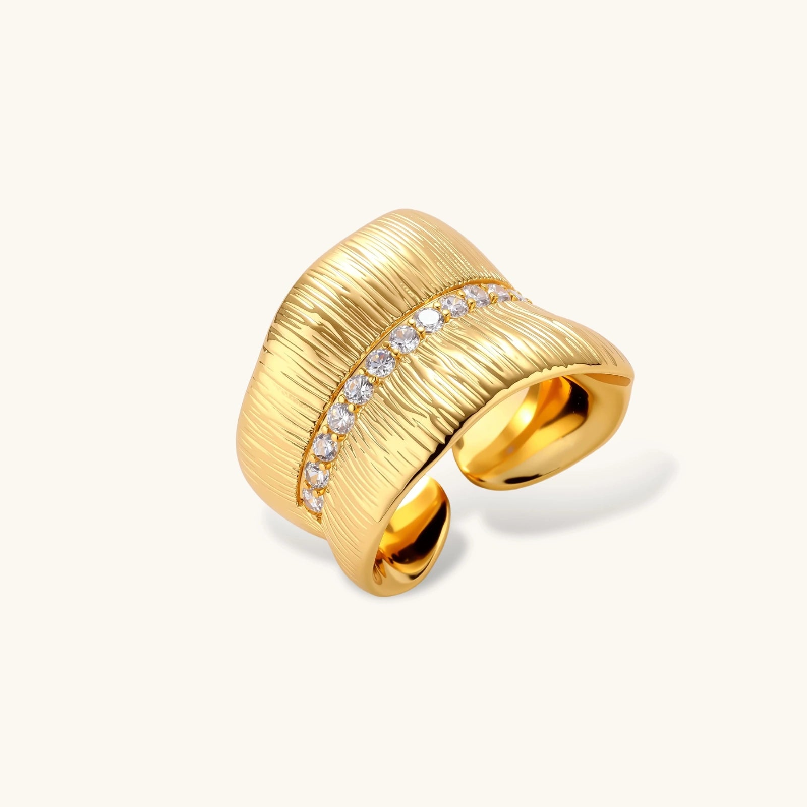 Adjustable gold-plated cuff ring with parallel ridged texture and diagonal row of sparkling zirconia stones on white background.