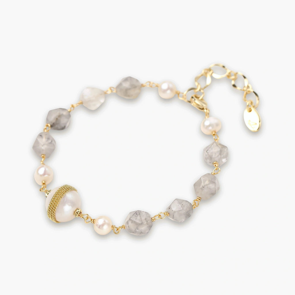 Bracelet with cloudy quartz beads, freshwater pearls, and gold-wrapped baroque pearl centerpiece on white background.
