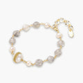 Bracelet with cloudy quartz beads, freshwater pearls, and gold-wrapped baroque pearl centerpiece on white background.