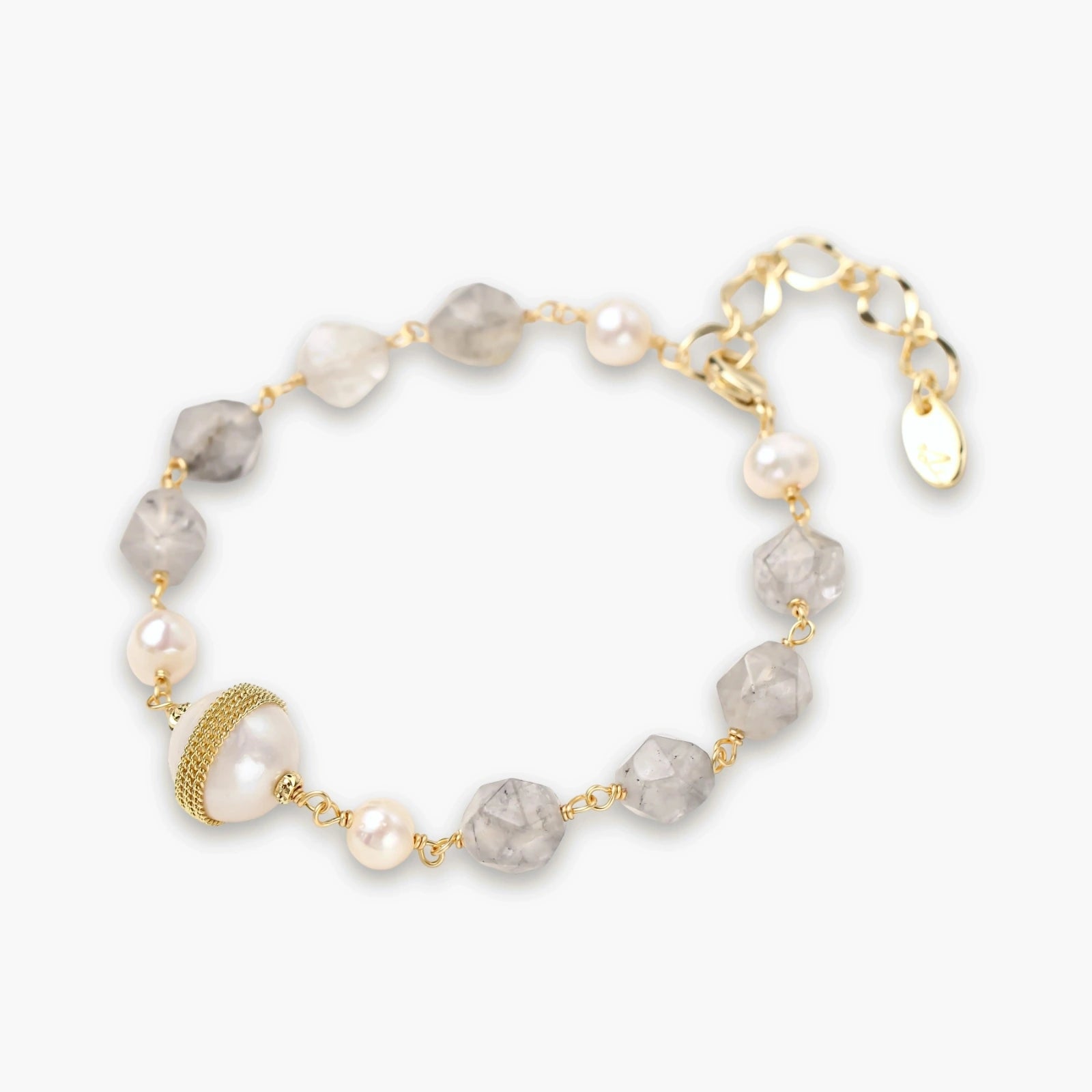 Bracelet with cloudy quartz beads, freshwater pearls, and gold-wrapped baroque pearl centerpiece on white background.