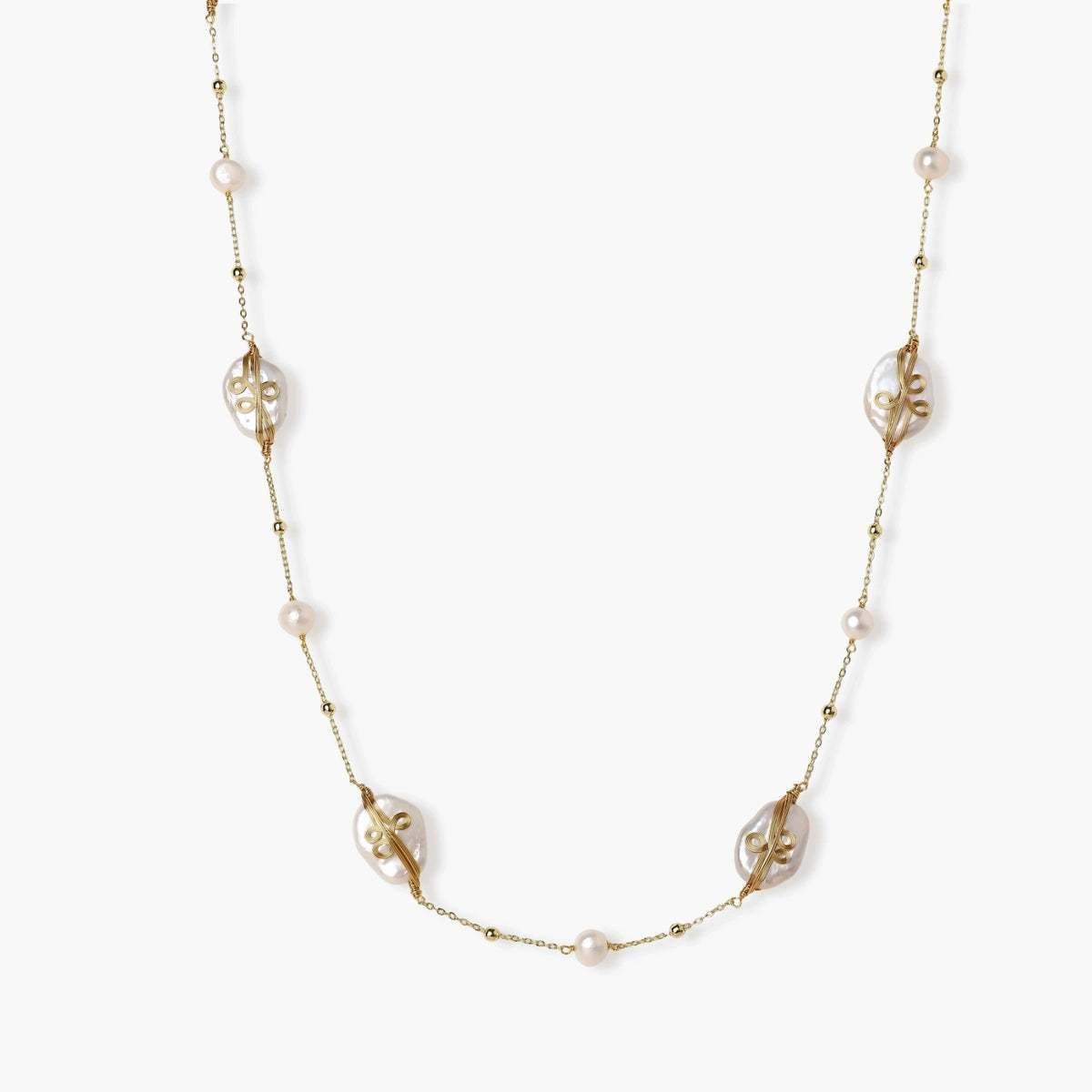 Long gold chain necklace with baroque pearls wrapped in leaf designs and small freshwater pearls spaced along the strand
