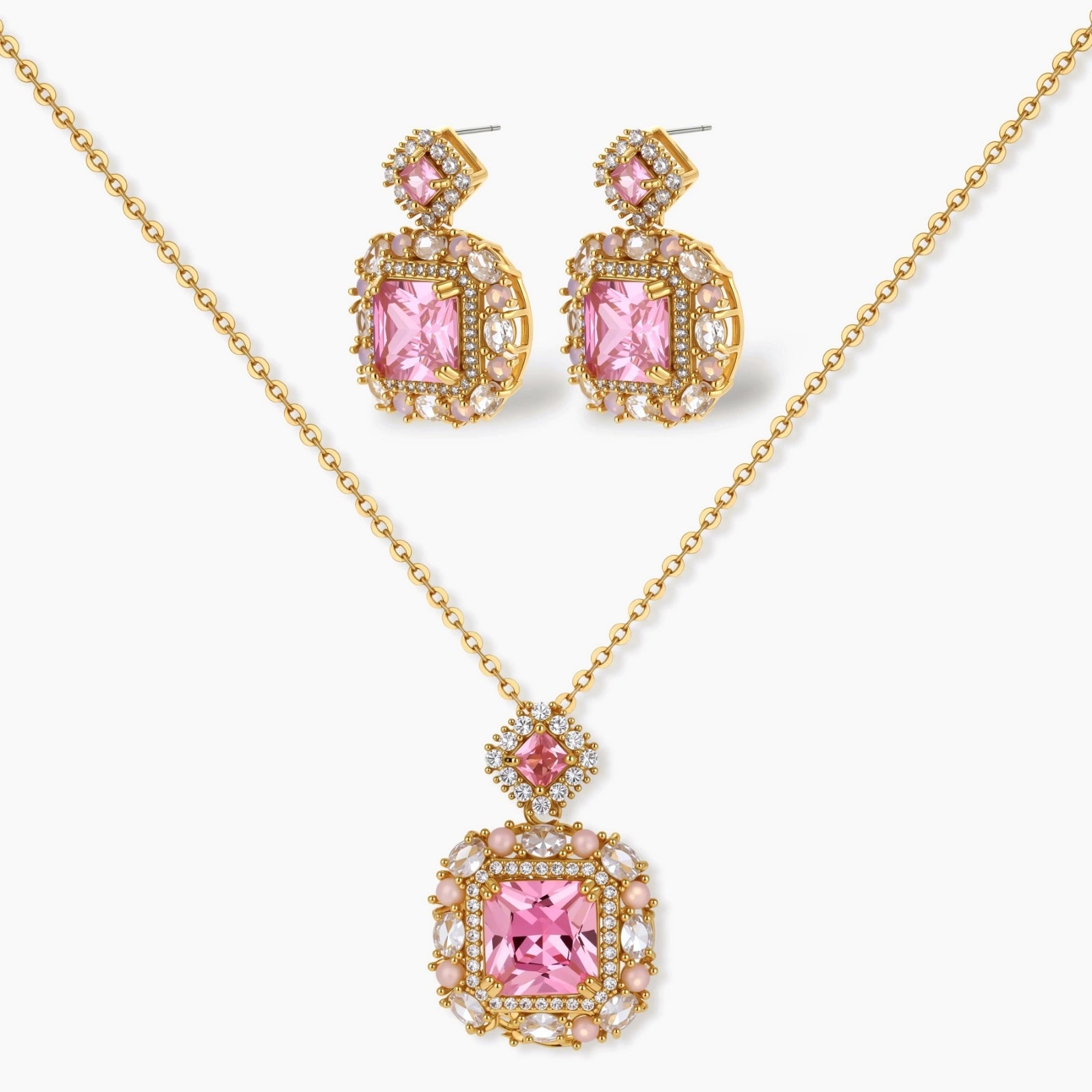 Ornate gold-plated jewelry set with rose pink zirconia center stones and crystal accents on cream background.